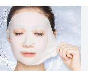 Wanita mengaplikasikan masker wajah putih dengan rileks di atas background biru lembut